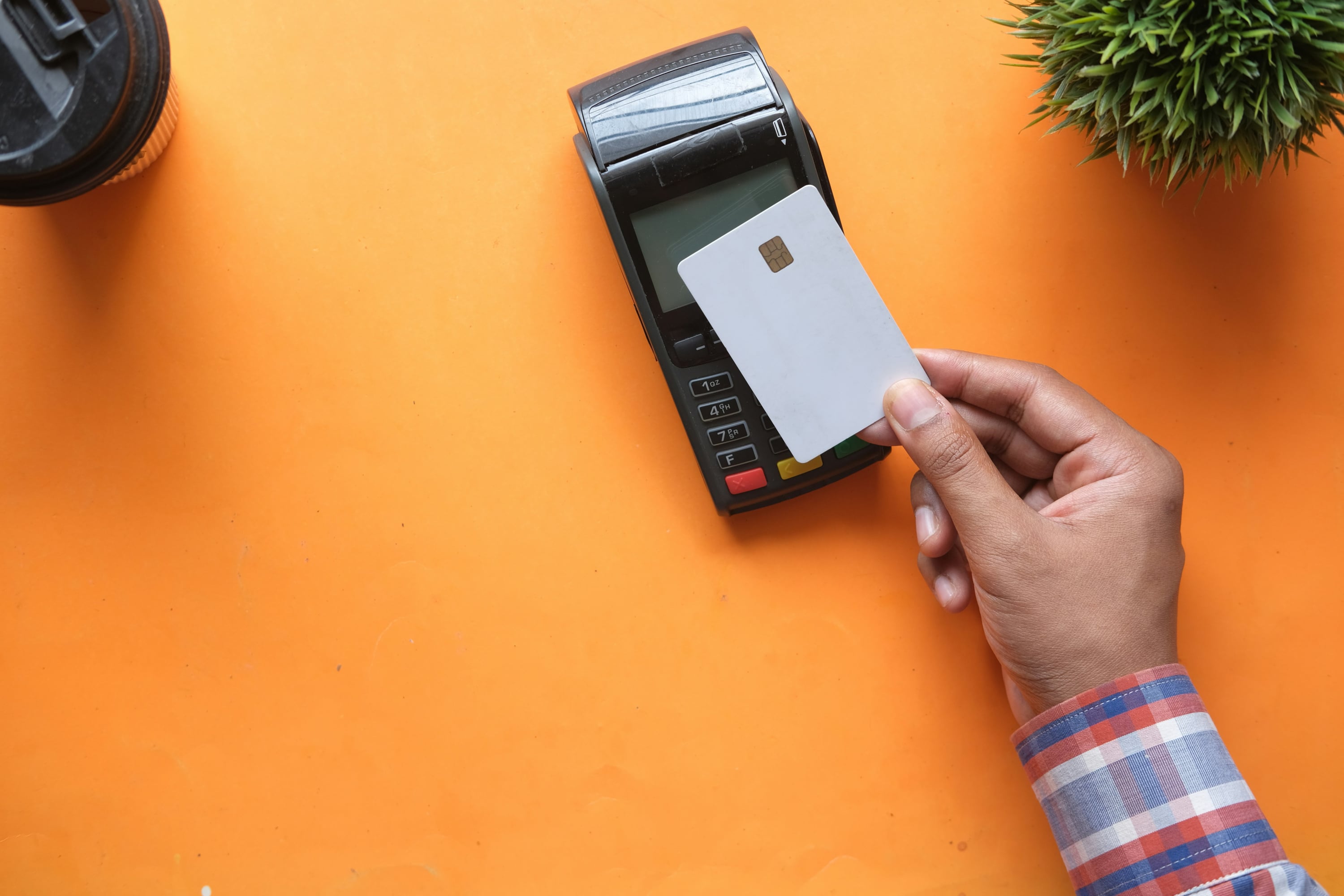 A hand holding a debit card over a contactless card reader